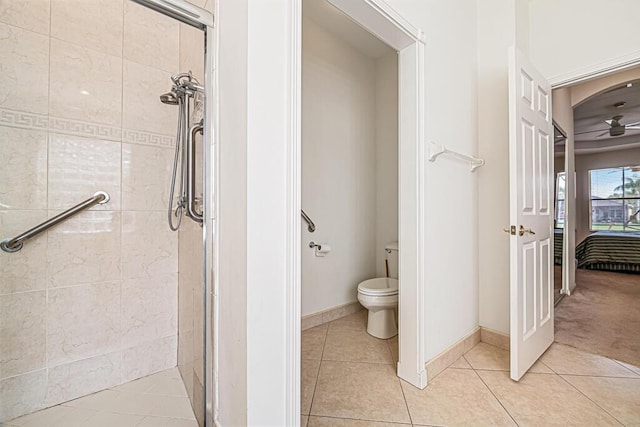 bathroom with tile patterned floors, toilet, ceiling fan, and an enclosed shower