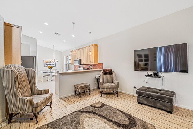 sitting room with a notable chandelier, light wood-type flooring, and lofted ceiling