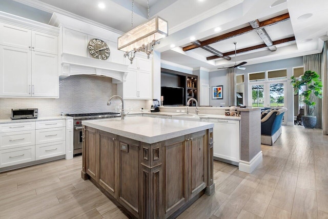 kitchen with french doors, an island with sink, beam ceiling, coffered ceiling, and white cabinets