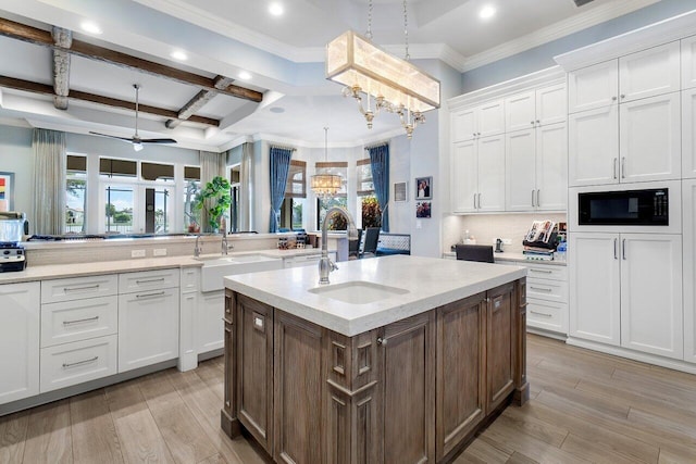 kitchen with pendant lighting, sink, ceiling fan, beamed ceiling, and coffered ceiling