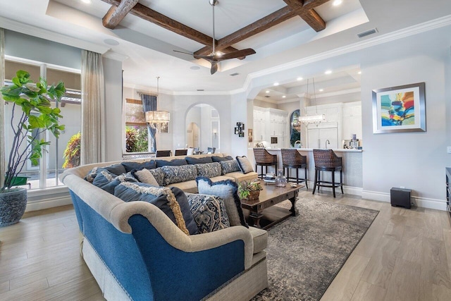 living room with beamed ceiling, coffered ceiling, light hardwood / wood-style floors, ceiling fan with notable chandelier, and crown molding