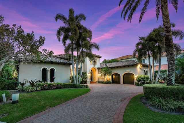 mediterranean / spanish-style home featuring a lawn and a garage