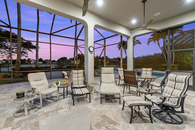 patio terrace at dusk with ceiling fan and a lanai