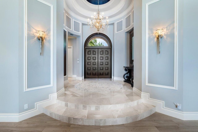 entrance foyer with a tray ceiling, crown molding, and an inviting chandelier