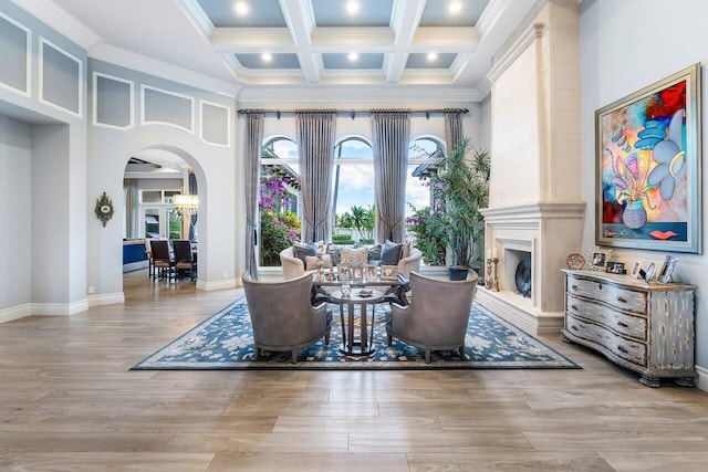 living room featuring light wood-type flooring, beam ceiling, coffered ceiling, a chandelier, and crown molding