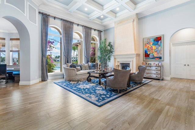 living room featuring light hardwood / wood-style floors, coffered ceiling, and a high ceiling