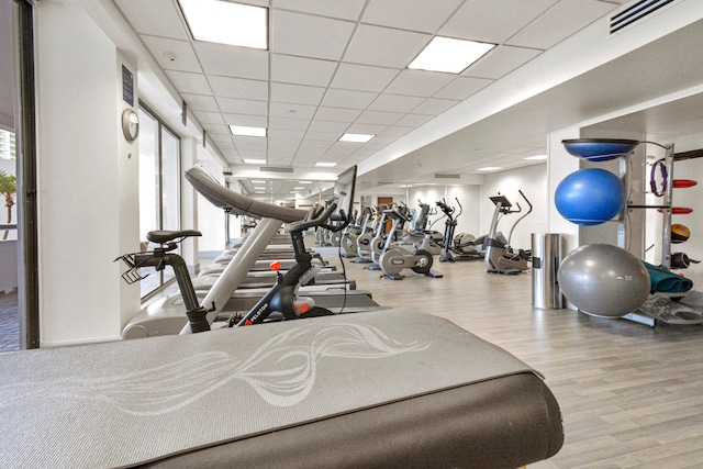 gym featuring light hardwood / wood-style flooring and a paneled ceiling