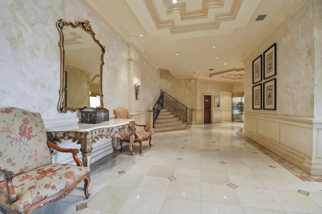 hallway with crown molding, light tile floors, a tray ceiling, and a high ceiling