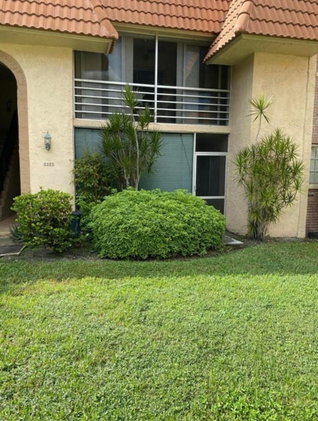 view of exterior entry with a balcony and a yard