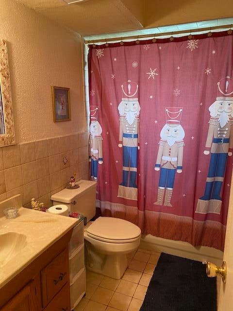 bathroom featuring tile walls, backsplash, tile floors, toilet, and vanity