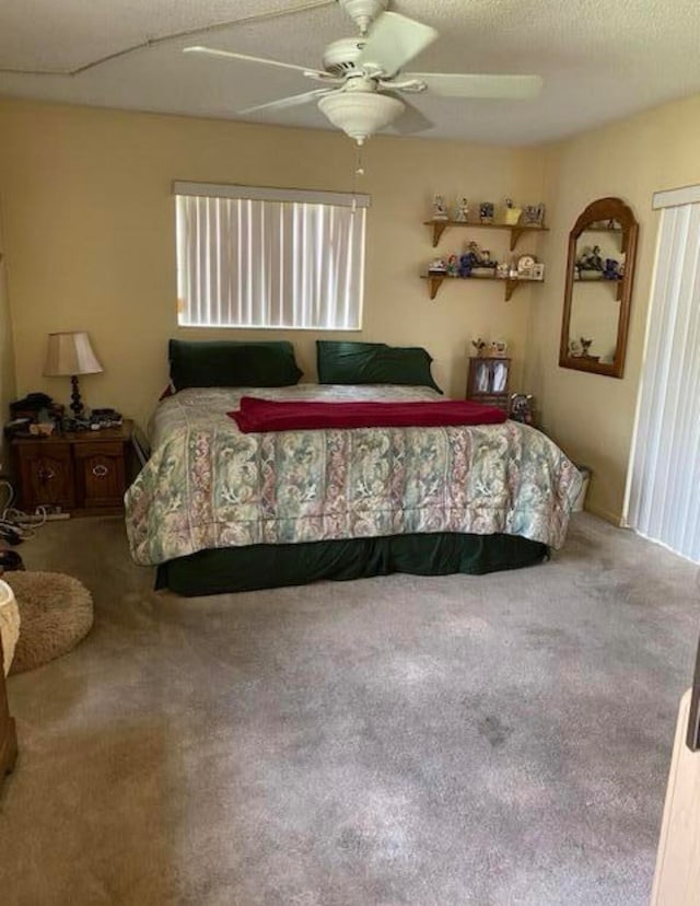 carpeted bedroom featuring ceiling fan and a textured ceiling