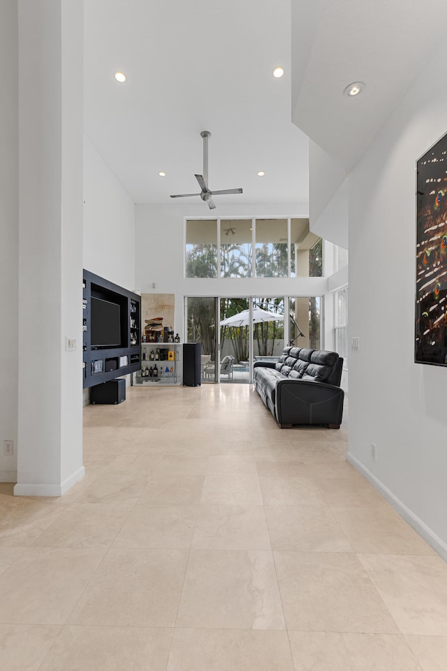 tiled living room featuring expansive windows and ceiling fan