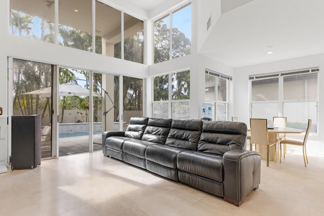 living room with a high ceiling, light tile floors, and a wealth of natural light