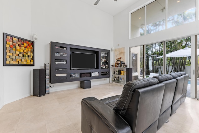 living room featuring a high ceiling, ceiling fan, and light tile floors