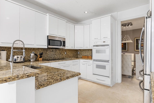 kitchen with white cabinets, backsplash, stone countertops, and stainless steel appliances