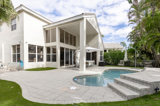 back of property with a fenced in pool and a patio area