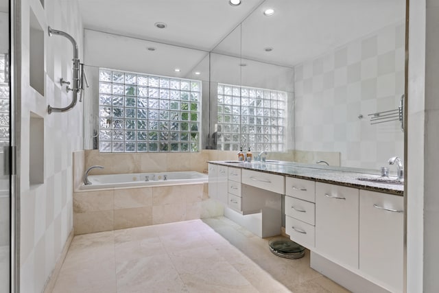 bathroom featuring tile walls, a relaxing tiled bath, tile flooring, and vanity