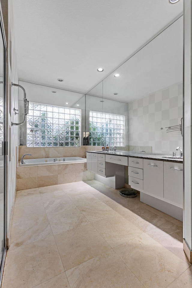 bathroom featuring tile floors, vanity, and a relaxing tiled bath