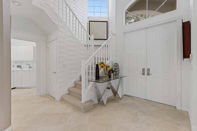 tiled entryway featuring a towering ceiling and sink