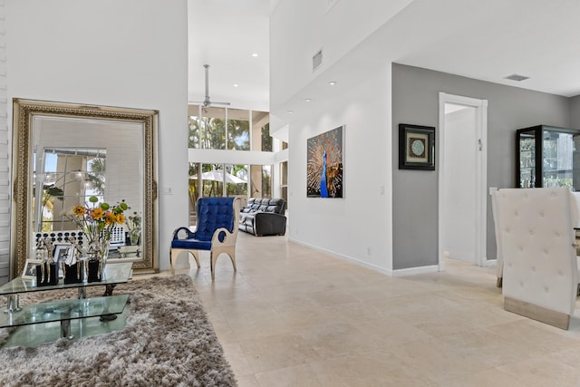 corridor with a high ceiling, light tile floors, and a wealth of natural light