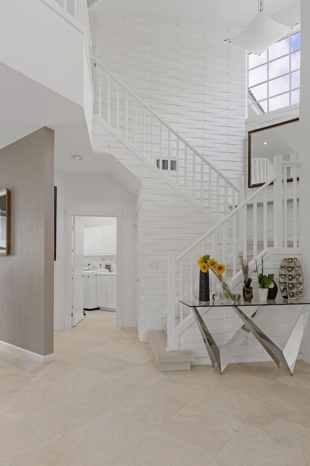 stairs featuring light tile flooring and a high ceiling