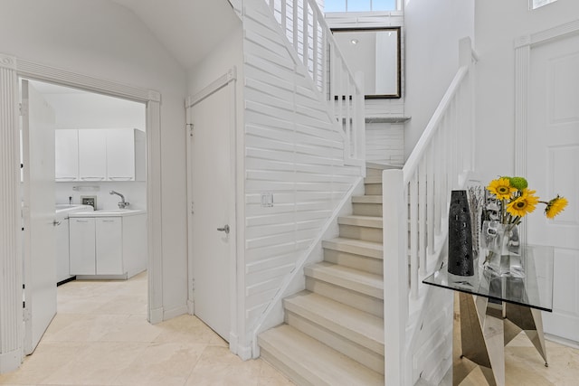 stairs featuring light tile floors, a towering ceiling, and washer / dryer