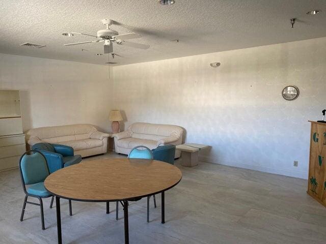 living area featuring ceiling fan and a textured ceiling