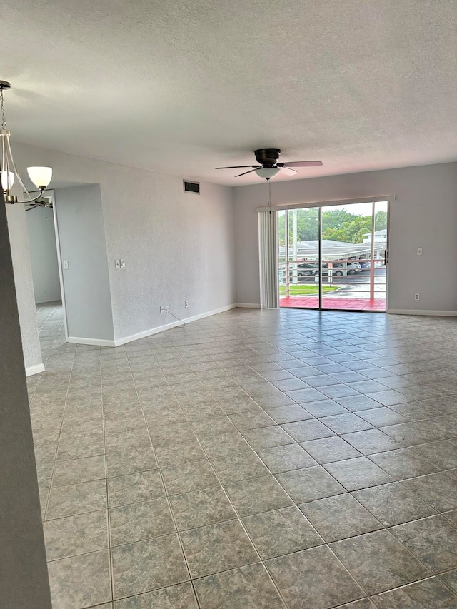 spare room featuring ceiling fan with notable chandelier, a textured ceiling, and light tile floors