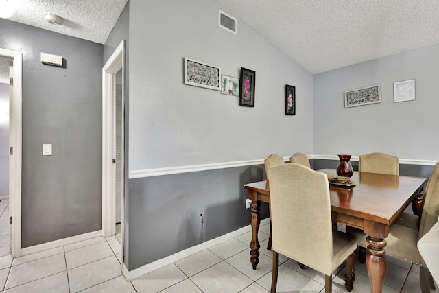 tiled dining space with vaulted ceiling and a textured ceiling