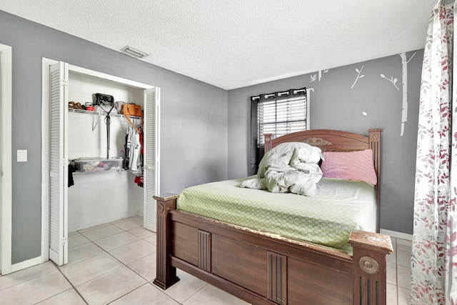 bedroom with a closet, light tile floors, and a textured ceiling