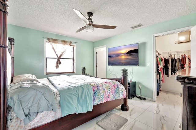 tiled bedroom featuring a closet, a textured ceiling, ceiling fan, and a spacious closet