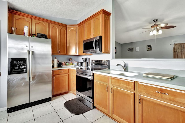 kitchen featuring appliances with stainless steel finishes, ceiling fan, light tile floors, a textured ceiling, and sink