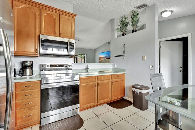 kitchen with appliances with stainless steel finishes, a textured ceiling, sink, light tile flooring, and lofted ceiling