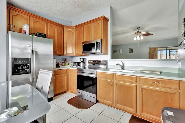 kitchen featuring appliances with stainless steel finishes, sink, ceiling fan, and light tile floors