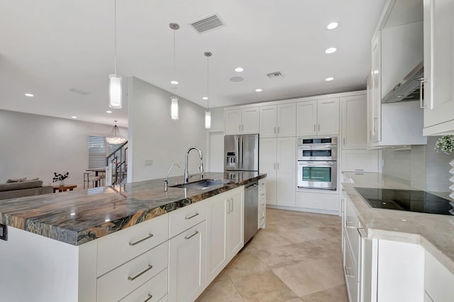 kitchen with appliances with stainless steel finishes, sink, pendant lighting, dark stone countertops, and a large island