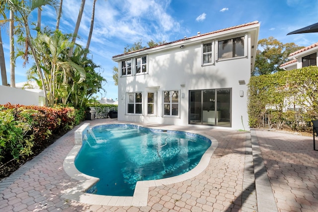 back of property featuring pool water feature, a fenced in pool, and a patio