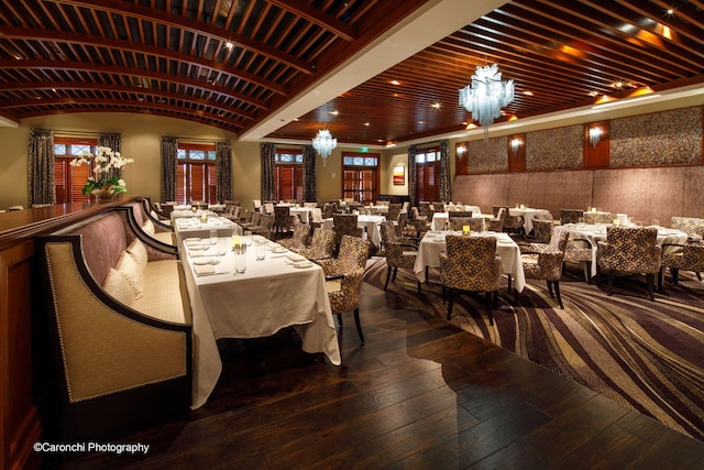 dining room with a chandelier, wood-type flooring, lofted ceiling, and brick ceiling