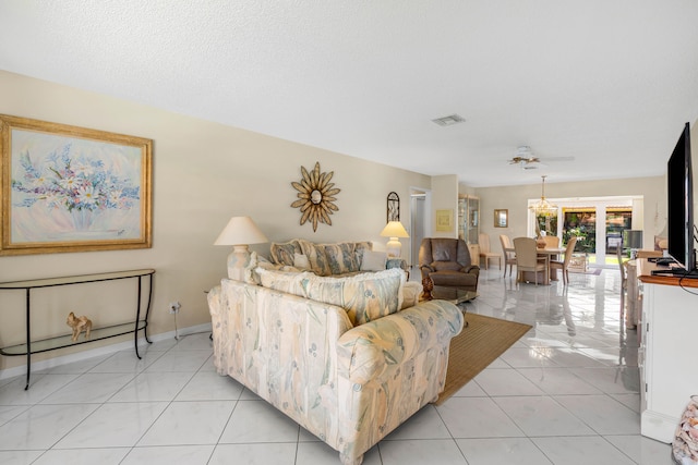 tiled living room with ceiling fan with notable chandelier