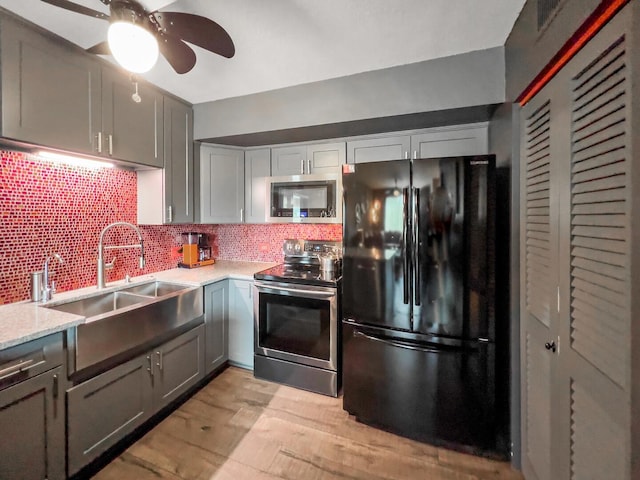 kitchen with appliances with stainless steel finishes, tasteful backsplash, light hardwood / wood-style flooring, ceiling fan, and sink