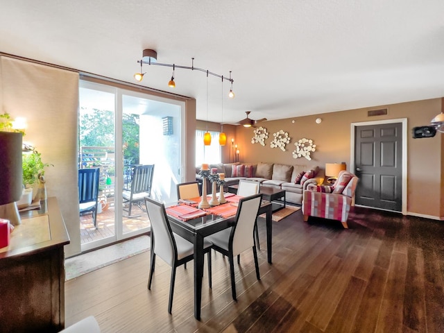 dining area with dark wood-type flooring and rail lighting