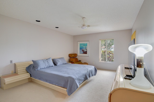 bedroom featuring a textured ceiling, ceiling fan, and light carpet