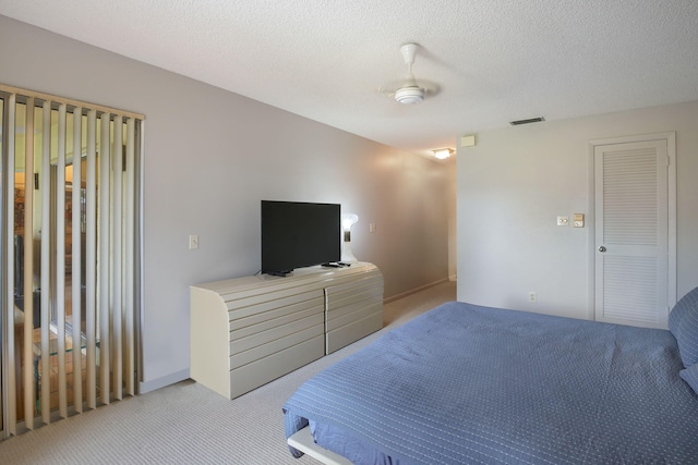 carpeted bedroom with a closet, a textured ceiling, and ceiling fan