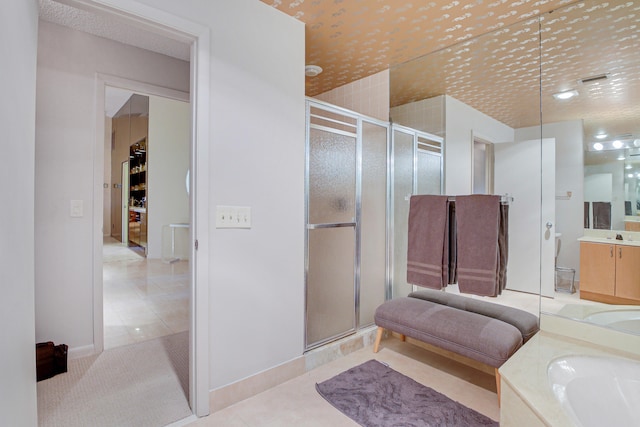 bathroom with a shower with shower door, tile flooring, and vanity