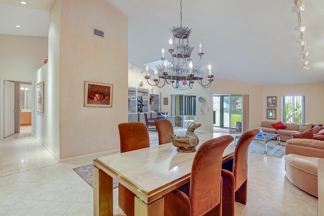 tiled dining space featuring rail lighting, high vaulted ceiling, and a notable chandelier