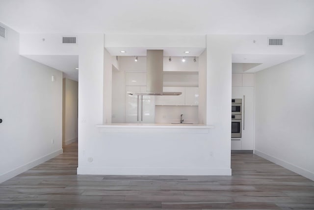 kitchen featuring sink, double oven, island range hood, white cabinets, and dark hardwood / wood-style flooring