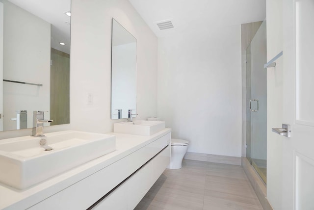 bathroom featuring vanity, tile patterned flooring, a shower with door, and toilet