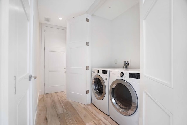 laundry area with independent washer and dryer and light hardwood / wood-style flooring