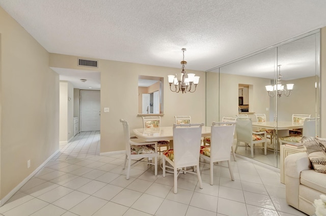 dining area with light tile patterned floors, a textured ceiling, and an inviting chandelier