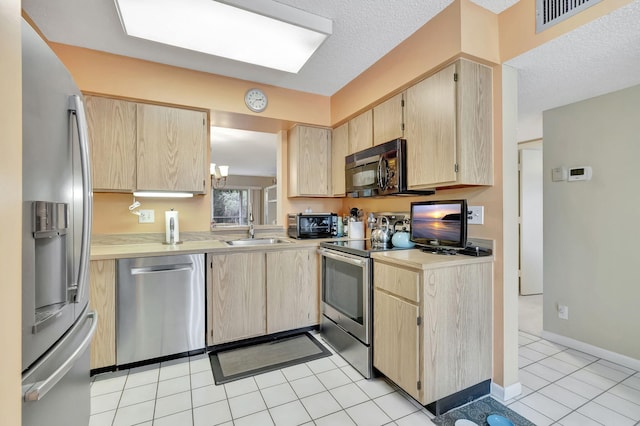 kitchen featuring a textured ceiling, sink, stainless steel appliances, and light brown cabinetry