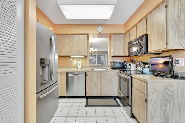 kitchen featuring sink, light brown cabinets, a chandelier, light tile patterned floors, and appliances with stainless steel finishes